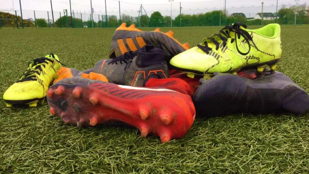 Abandoned football boots on an astro turf pitch.